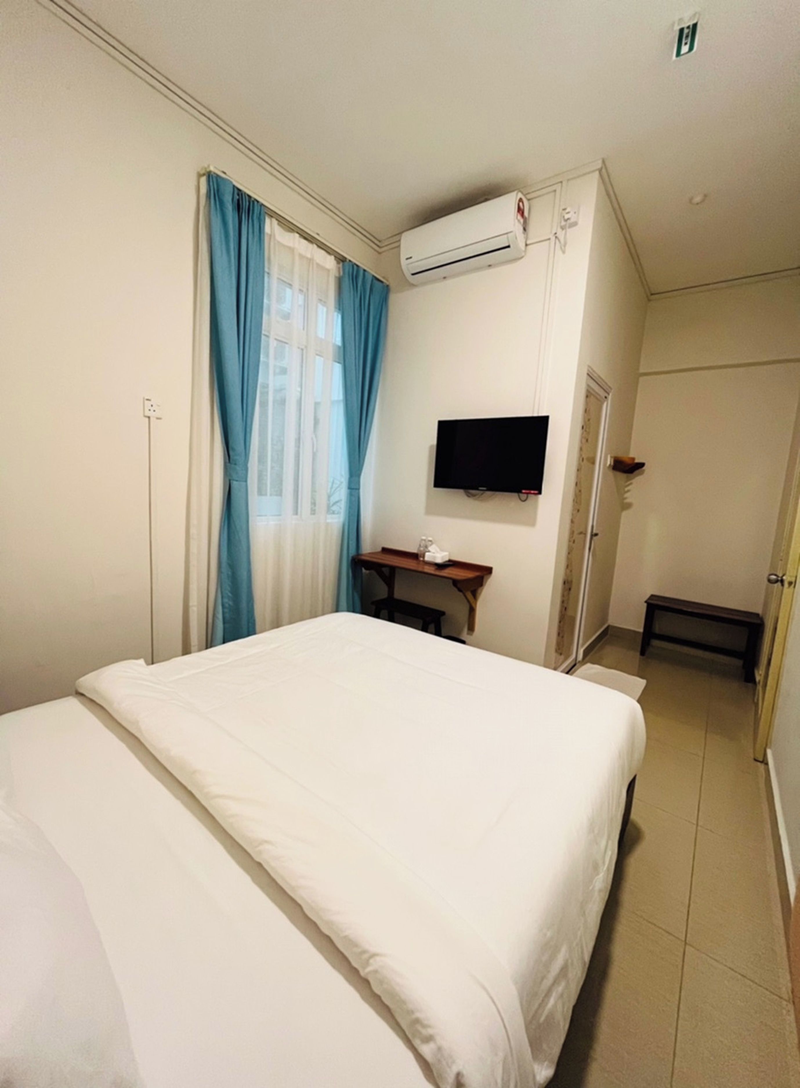 Ein Hotelzimmer mit einem Bett, einem an der Wand montierten Fernseher und einer Klimaanlage.