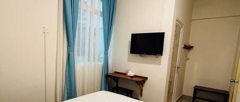 Una habitación de hotel con una cama, un televisor montado en la pared y un equipo de aire acondicionado.