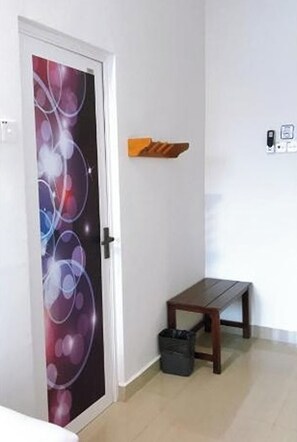 Una habitación con una puerta decorada con un diseño abstracto y colorido, un pequeño banco de madera y un estante fijado a la pared.
