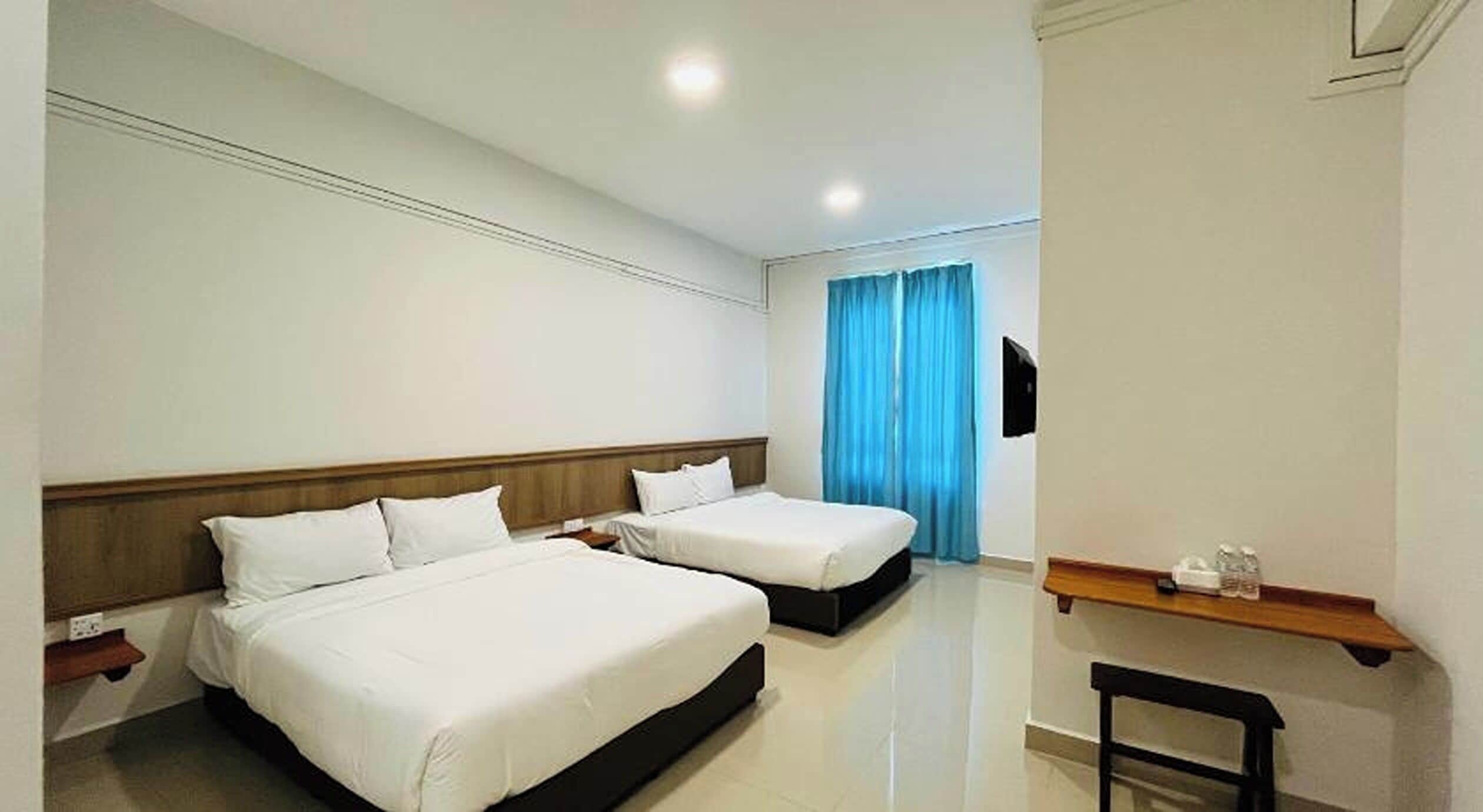 A hotel room with two beds, a flat-screen TV, a wooden shelf, and a chair.