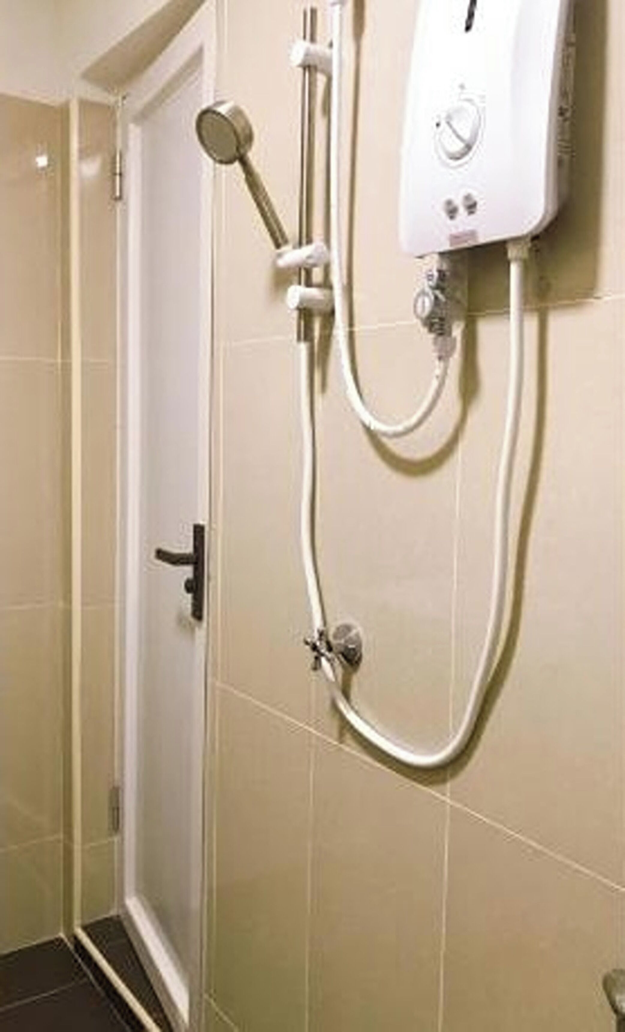 A bathroom with a shower unit, a door, and tiled walls.