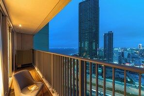 A balcony with a view of a cityscape and the ocean at dusk. - Terra Calm Soleil Beachfront Residence (Da Nang)