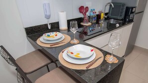 Una cocina con una mesa de comedor para dos personas, un microondas y una cafetera.