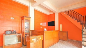 Un espace d’accueil comprenant un bureau en bois, une vitrine et un escalier avec une rampe noire.