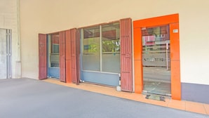 Un bâtiment doté d’une grande porte vitrée, d’un portail en métal et d’une petite fenêtre.