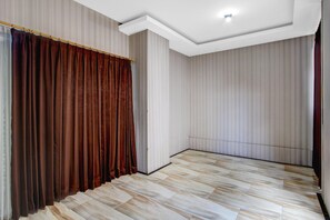 Une pièce avec un plafond en pente, un plancher en bois et un rideau sur un des murs.
