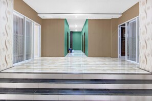 Un couloir doté d’un sol carrelé, de murs verts et d’un escalier menant à l’étage supérieur.