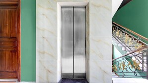 A marble elevator with a green wall and a wooden door to the left.