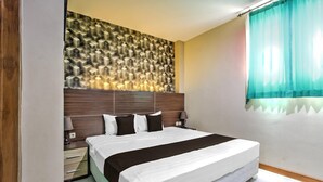 A bedroom with a bed, bedside tables, a wall with a geometric pattern, and a window with curtains.