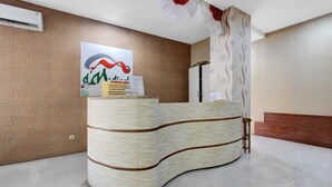 A reception desk with a curved design, a wall-mounted air conditioner, and a poster on the wall.