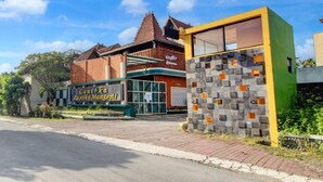 A building with a sign that reads 'Cantika Pastika Mangestu' and a modern structure with a stone facade.