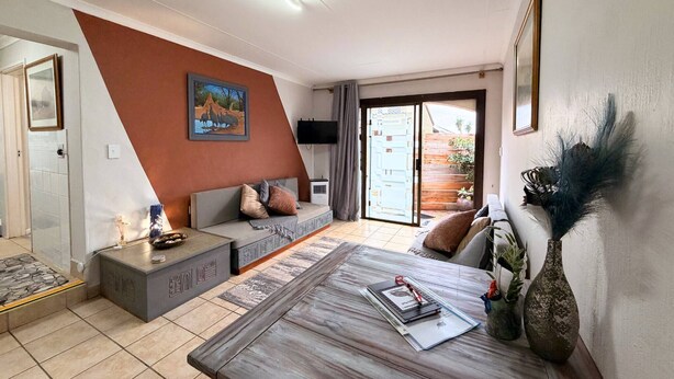 A modern living room with a sofa, coffee table, and decorative items. - Serene 1-bedroom Apartment in Plettenberg Bay - Guinea's Nest (Plettenberg Bay)
