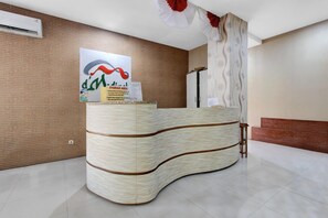 Un comptoir d’accueil au design incurvé, un climatiseur fixé au mur et une affiche sur le mur.