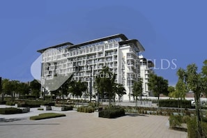 Ein modernes, mehrgeschossiges Hotel mit einer markanten, geschwungenen Fassade, umgeben von angelegten Gärten und einem gepflasterten Weg.