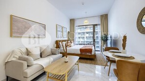 A modern living room with a sofa, coffee table, and dining area. - Bloomfields Studio Oasis Masdar (Abu Dhabi)