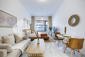 Ein modernes Wohnzimmer mit Sofa, Couchtisch, Esstisch und Stühlen. Ein Bett mit Blick ins Freie.
