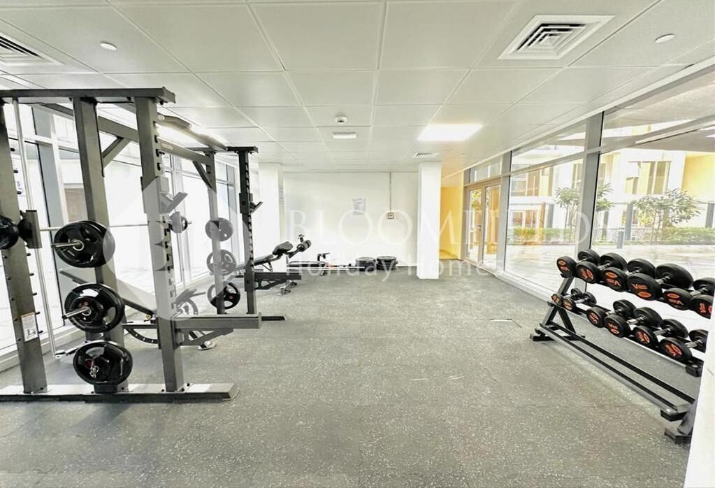 Et fitnesscenter med styrkeløftudstyr, store vinduer og et rent, moderne interiør.