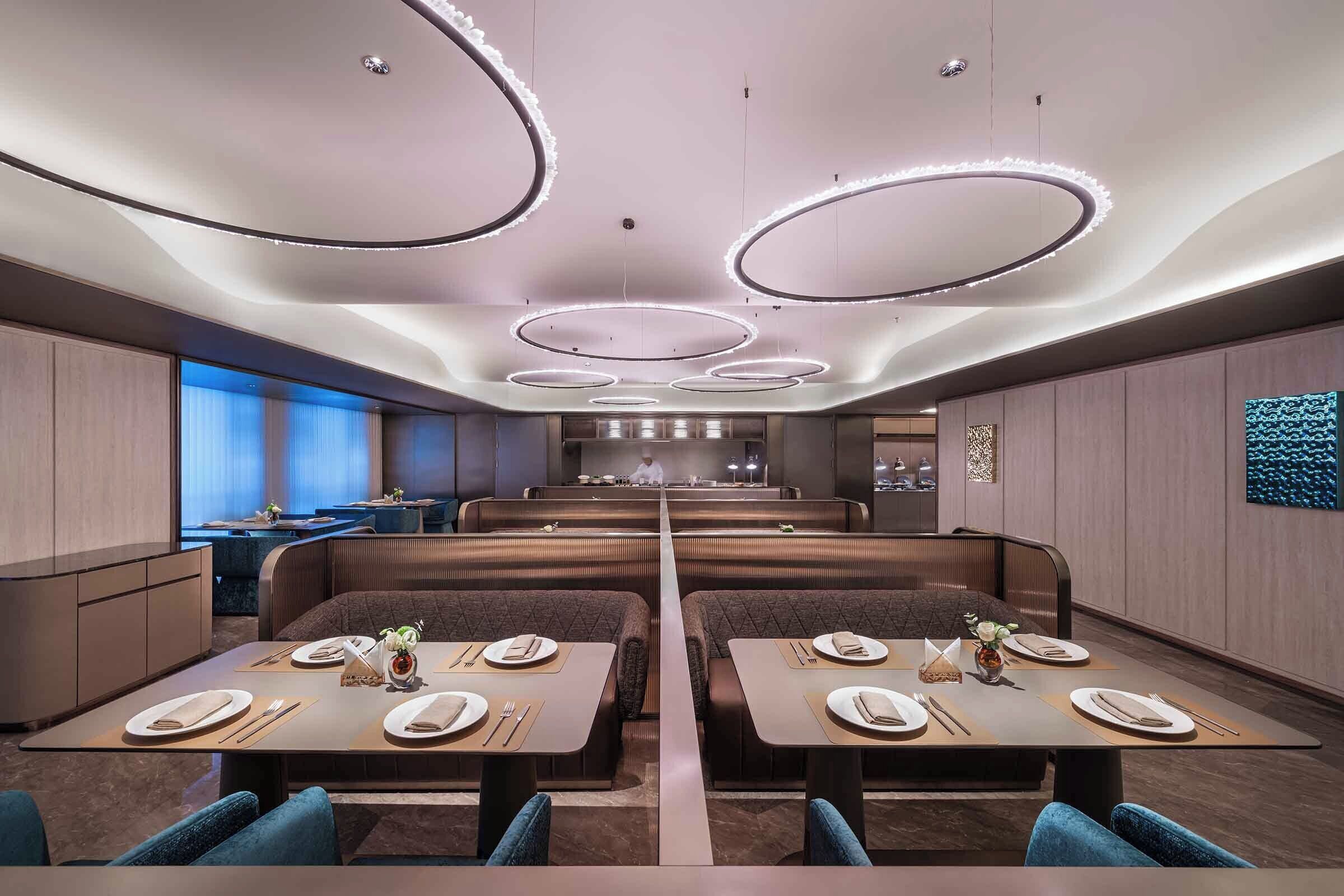 Un restaurante moderno con zona de comedor central, cabinas y un bar al fondo.