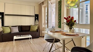 Ein modernes Wohnzimmer mit einer Couch, einem Esstisch und Blick auf die Stadt.