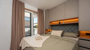 Ett modernt hotellrum med en säng, ett nattduksbord, en sänggavel och utsikt över omgivningarna.