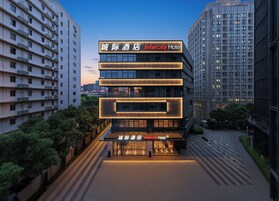 A modern hotel building with illuminated signage, multiple floors, and a surrounding urban environment.