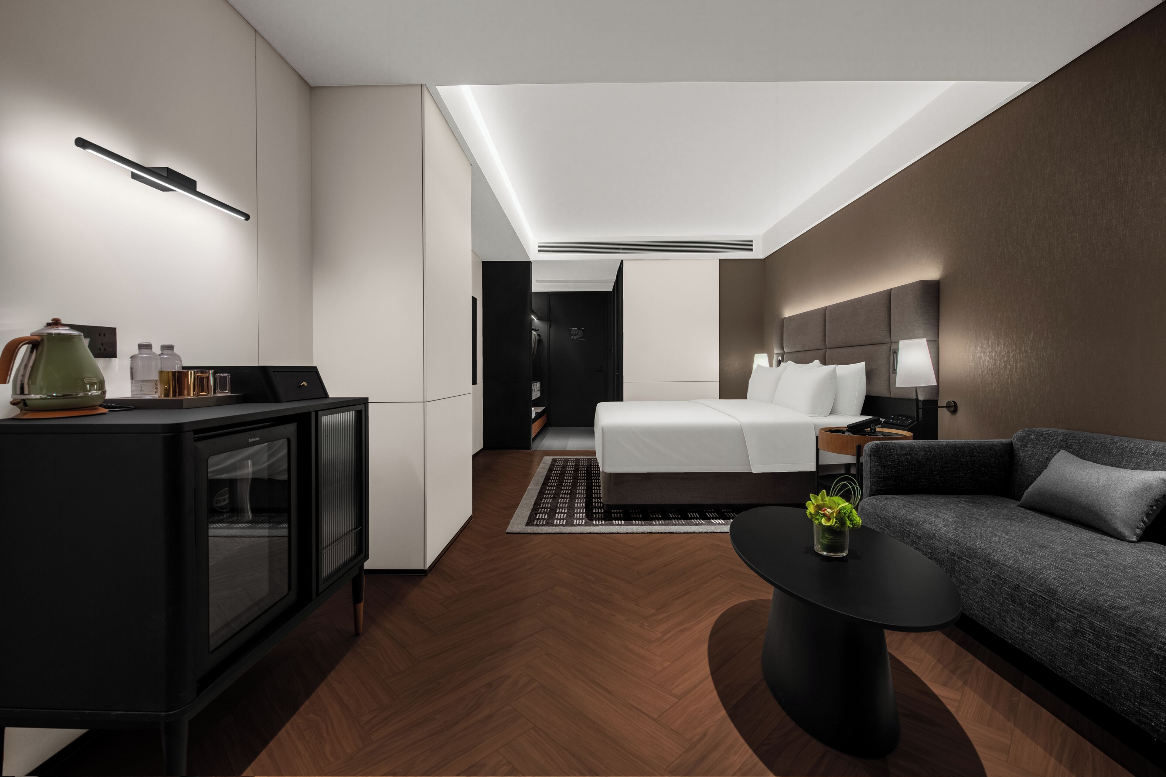 Una habitación de hotel moderna con una cama, un sofá, una mesa de centro, un televisor y una kitchenette.