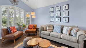 A living room with a sofa, armchairs, a coffee table, and a wall with framed pictures. - True Blue Golf & Beach Getaway (Pawleys Island)