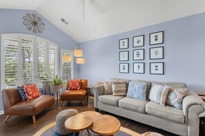 A living room with a sofa, armchairs, a coffee table, and a wall with framed pictures. - True Blue Golf & Beach Getaway (Pawleys Island)
