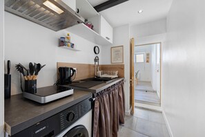 Cocina compacta con lavadora integrada, cafetera y hervidor.
