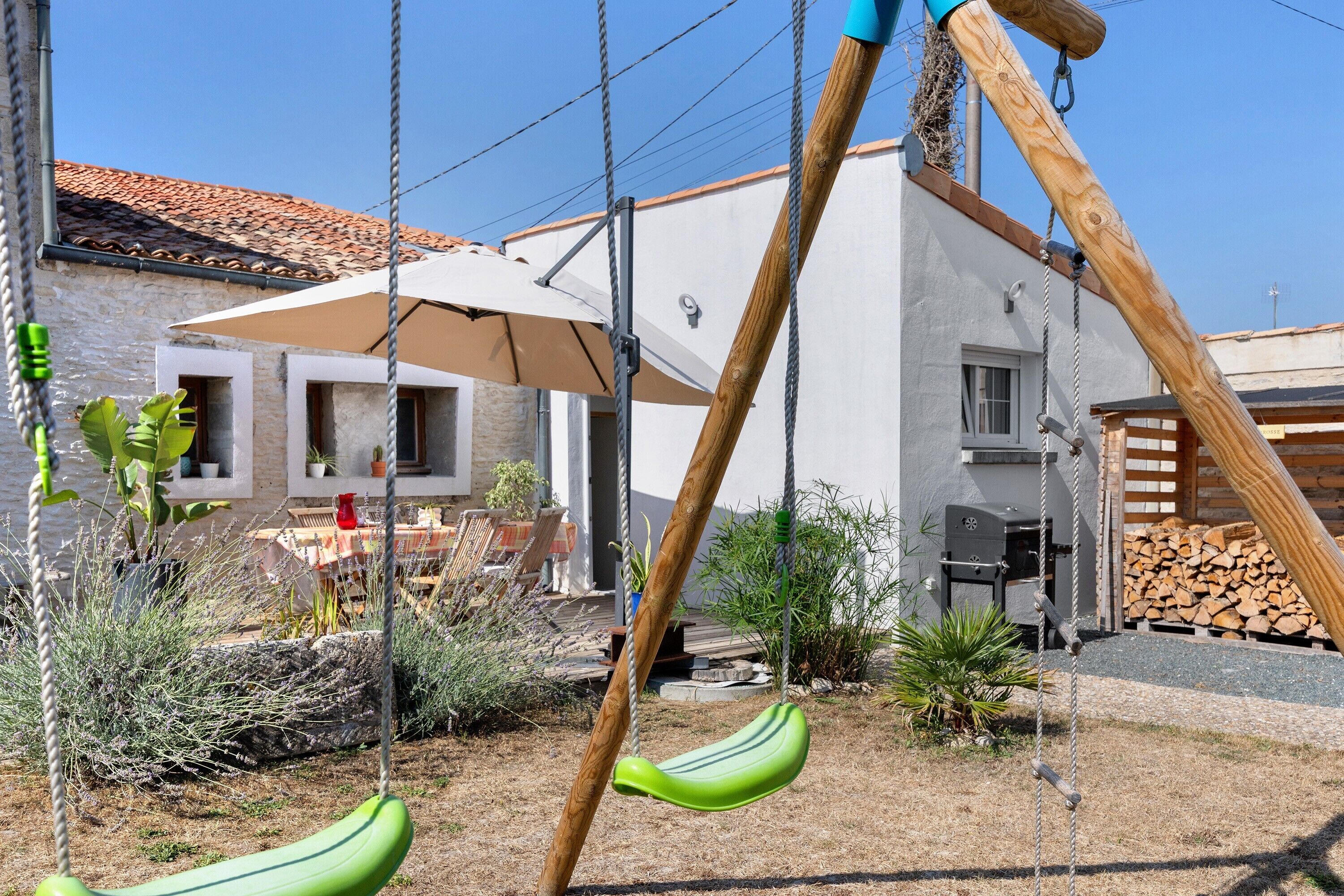 A wooden swing set with a green seat, a white umbrella, and a stone building in the background.
