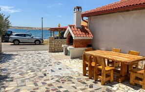 A patio area with a mosaic floor, a brick oven, and a table with chairs. - 2 bedroom cozy apartment in Kustici (Kustici)