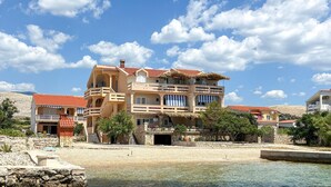 Um hotel de vários andares com varandas, piscina e vista para a praia.