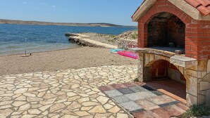Um pátio de pedra leva a uma pequena construção de tijolos com vista para o mar.