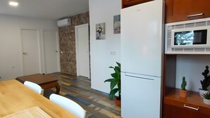 Een moderne keuken met een magnetron, een koelkast en een eethoek met een tafel en stoelen.