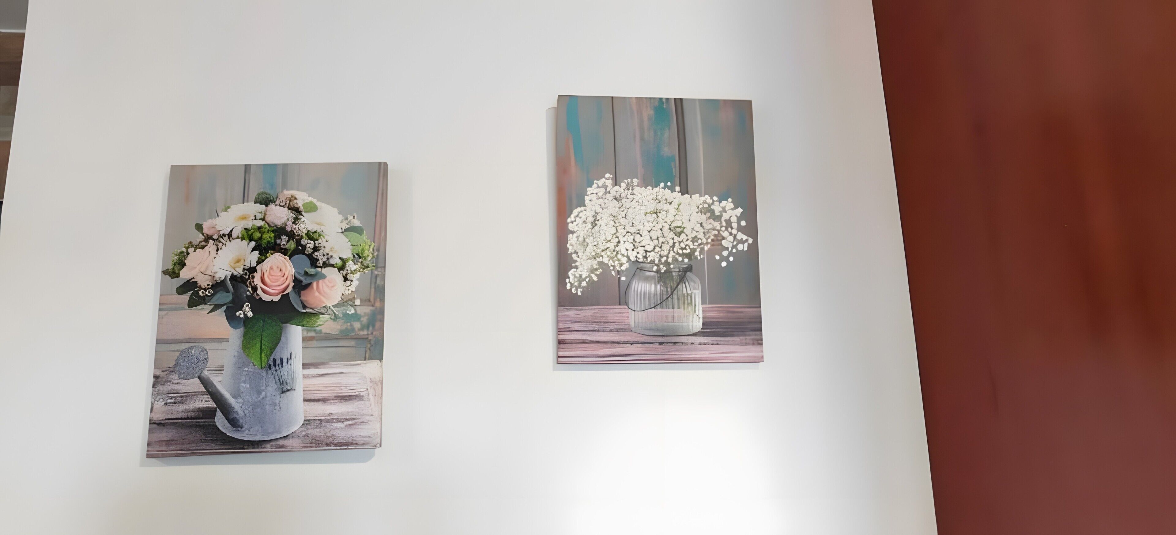 Två målningar som föreställer vaser med blommor, hängda på en vägg.