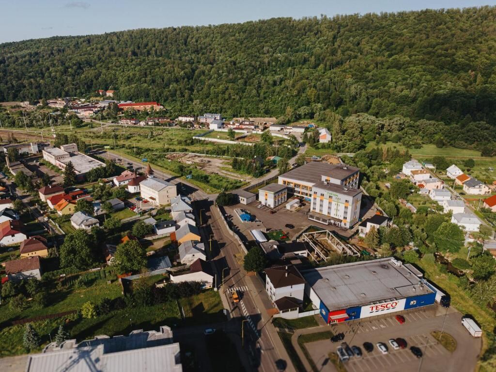 Vista aérea de un pueblo con diversos edificios, incluyendo una gran tienda Tesco, rodeado de viviendas y zonas verdes.