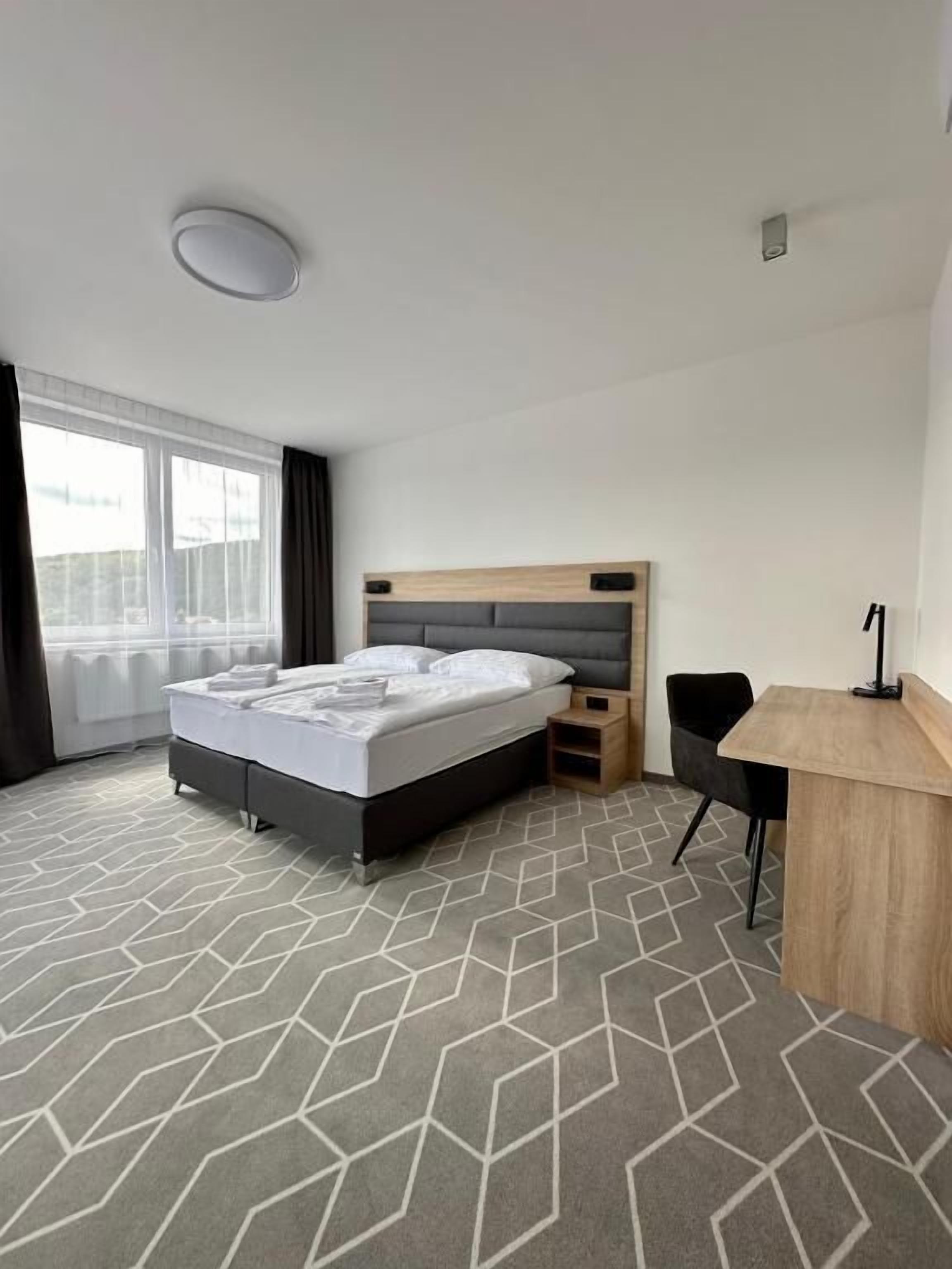 A hotel room with a bed, a desk, and a chair.