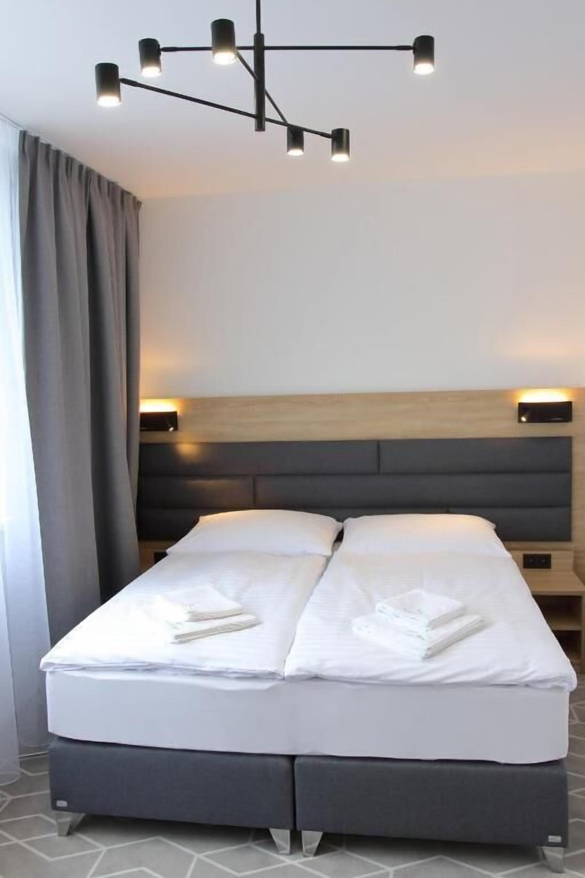 Ein modernes Hotelzimmer mit einem Bett, Nachttischlampen und einem Kopfteil.