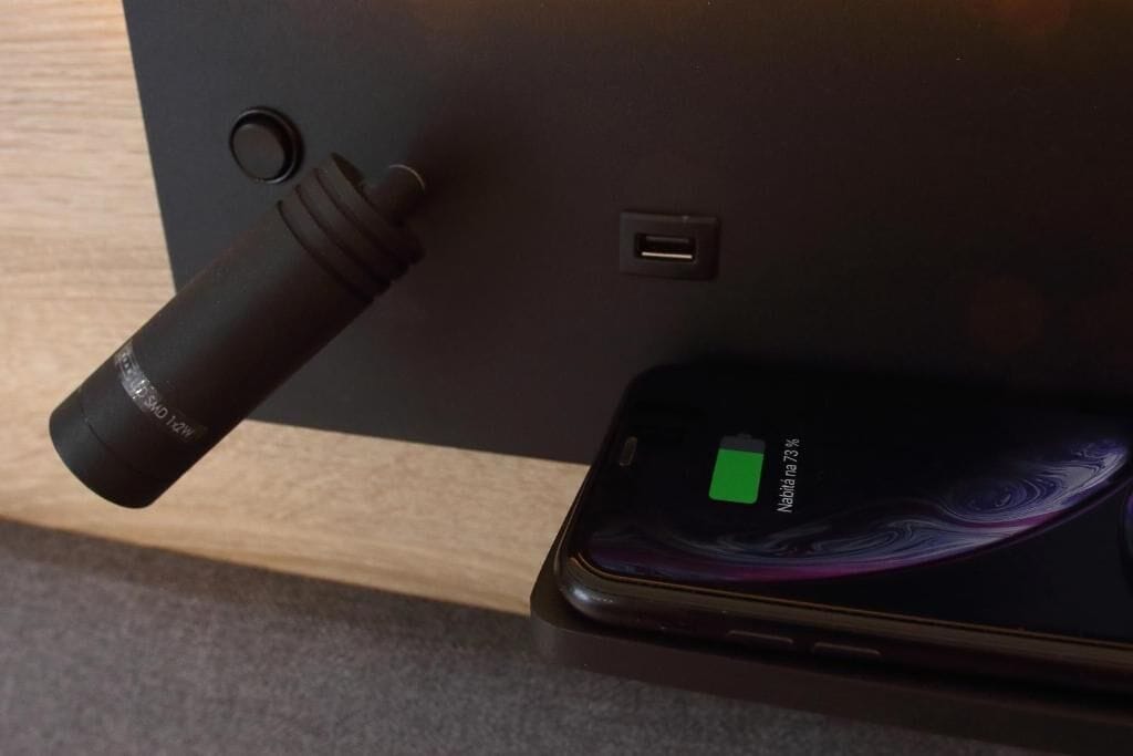 Un teléfono inteligente con un icono de batería verde, un puerto USB y una cámara sobre una superficie negra.