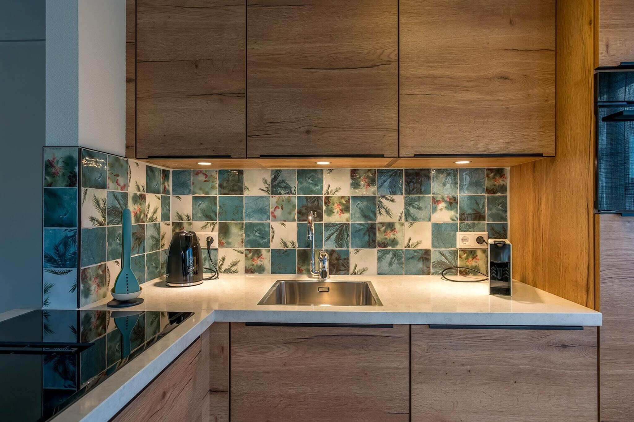 A modern kitchen with wooden cabinets, a tiled backsplash, and a stainless steel sink.