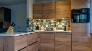 Una cocina moderna con armarios de madera, salpicadero de azulejos y horno empotrado.