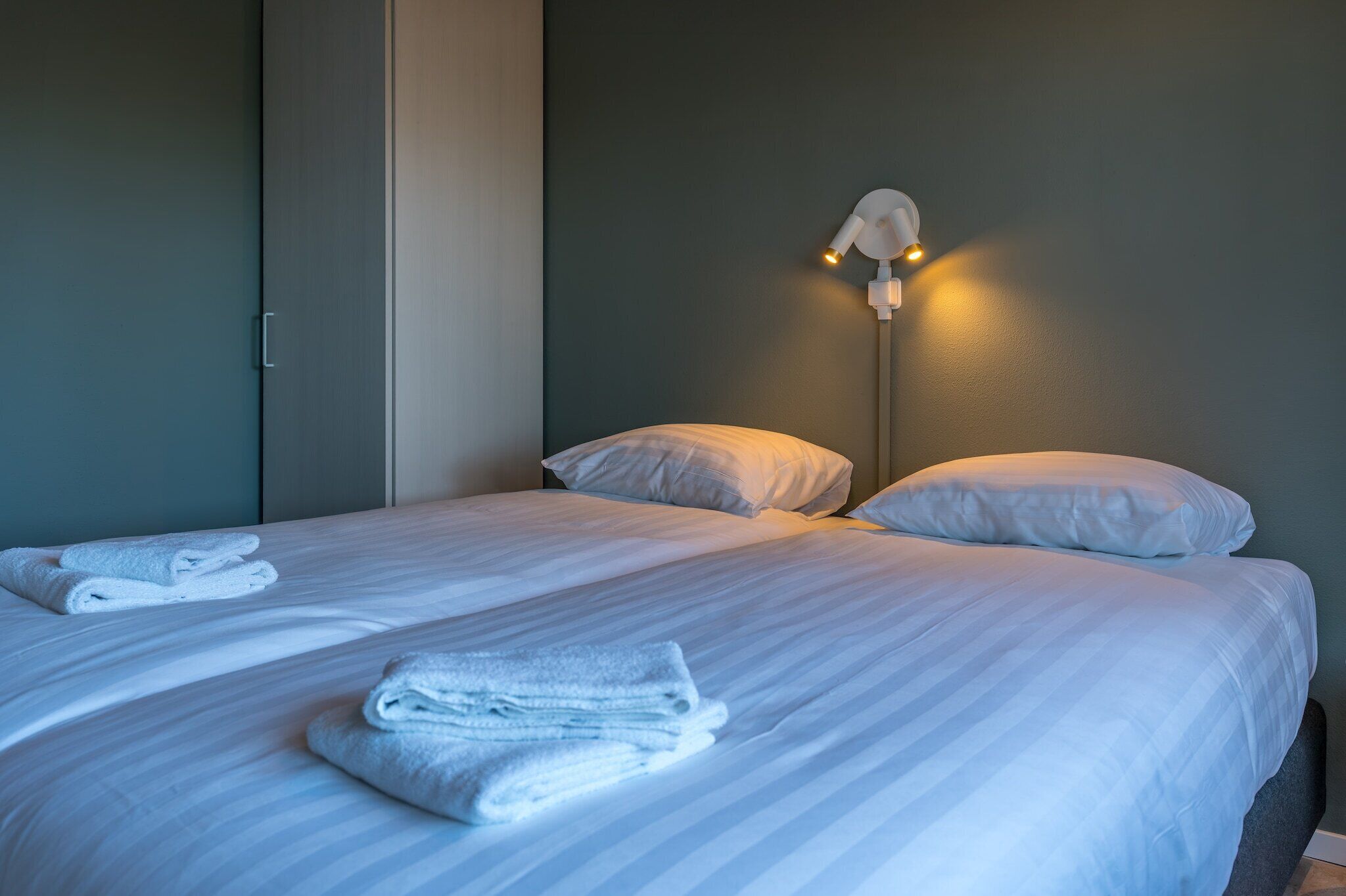 Ein Hotelzimmer mit Bett, Kissen und einer Wandlampe.