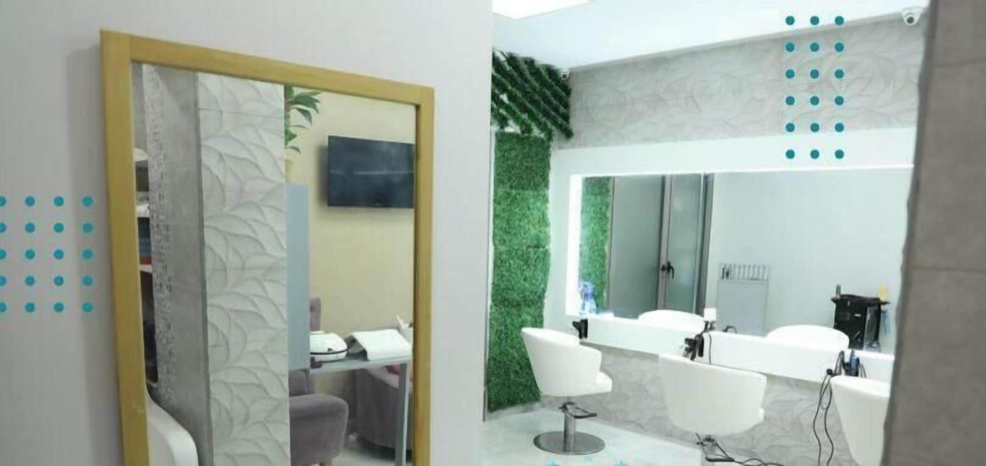 A modern bathroom with a large mirror, two sinks, and a green wall.