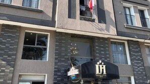 Un hotel de varios pisos con balcones, una fachada comercial y un cartel que indica un restaurante.