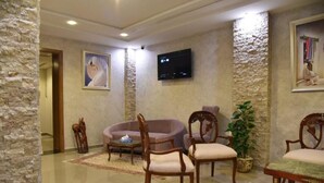Un vestíbulo con paredes de piedra, un televisor de pantalla plana y varios sillones y sofás de madera.