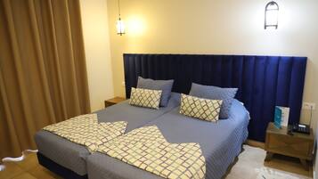 Cama doble con ropa de cama estampada, dos mesitas de noche y una lámpara de pared.
