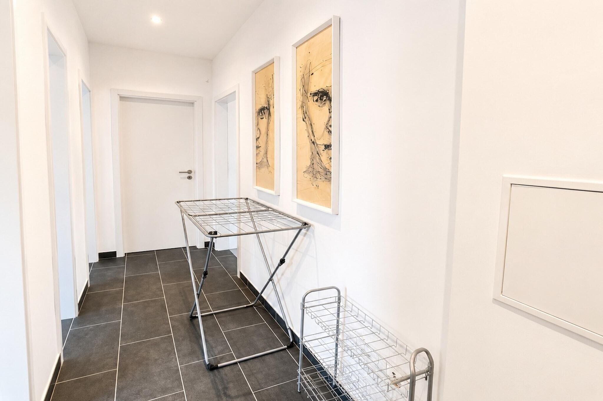 Un couloir avec un étendoir, une porte et deux œuvres d’art encadrées accrochées au mur.