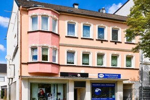 A building with a pink facade, multiple windows, and a sign for a sanatorium. - Apartment für Reisende und Monteure (Barmen)