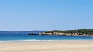 Una spiaggia con cieli sereni, mare calmo e scogliere rocciose.