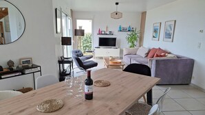 Un soggiorno moderno con un tavolo da pranzo in legno, un divano, una TV e un'ampia finestra.